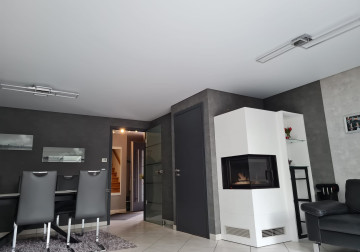 Spanndecke in Weiß-Matt mit dunkelgrauem Design und Kamin im Wohnzimmer für eine gemütliche Atmosphäre